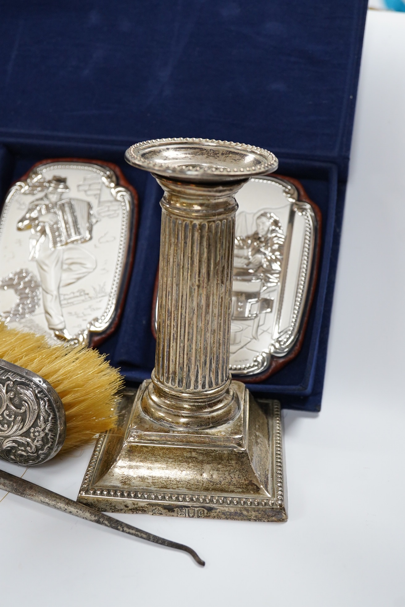 A pair of late Victorian silver dwarf candlesticks, by William Hutton & Sons, London, 1898, 13cm, weighted, together with a silver mounted button hook and clothes brush and a cased set of four 850 white metal mounted wal